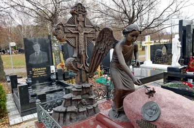 Возлагающая цветок на надгробье скульптура ангела